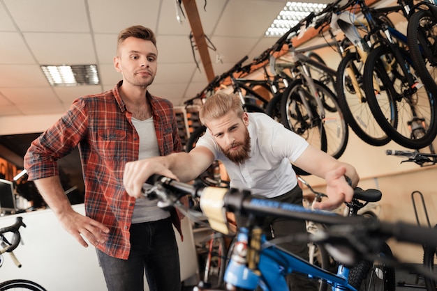 Le consultant montre son vélo au client dans le magasin de sport.