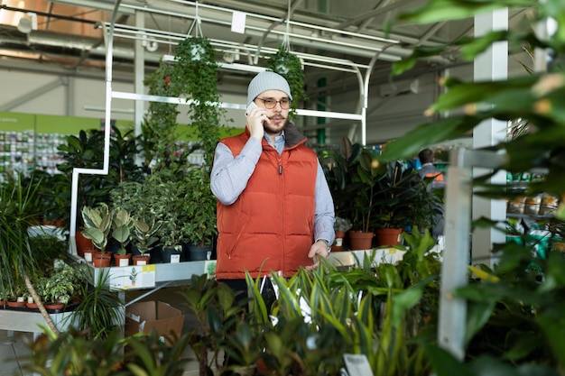 Consultant parlant au téléphone dans un magasin de plantes en pot et de fleurs fraîches