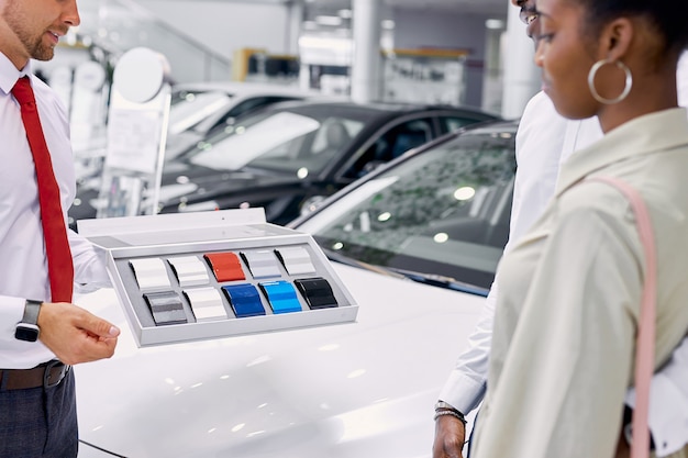 Un Consultant Professionnel Caucasien Confiant Montre La Palette De Couleurs Des Voitures Aux Clients