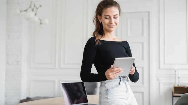 Une consultante brune travaille dans un bureau et utilise une tablette