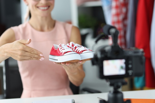 Une consultante-vendeuse montre à la caméra des chaussures de sport rouges. Choix des enfants du concept de chaussures de sport