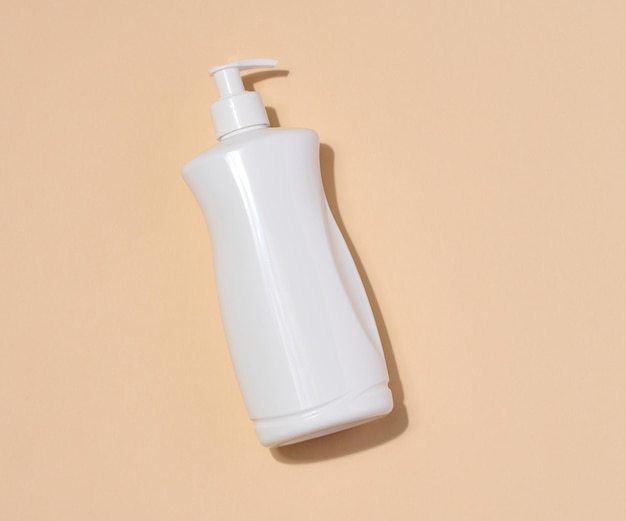 Container en plastique blanc avec une pompe pour produits liquides sur fond beige Container pour cosmétiques crème savon