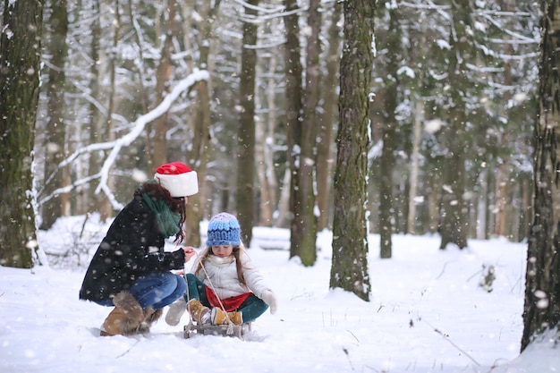 Conte de fées d'hiver une jeune mère et sa fille font du traîneau dans la forêt