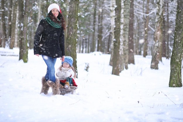 Conte de fées d'hiver une jeune mère et sa fille font du traîneau dans la forêt