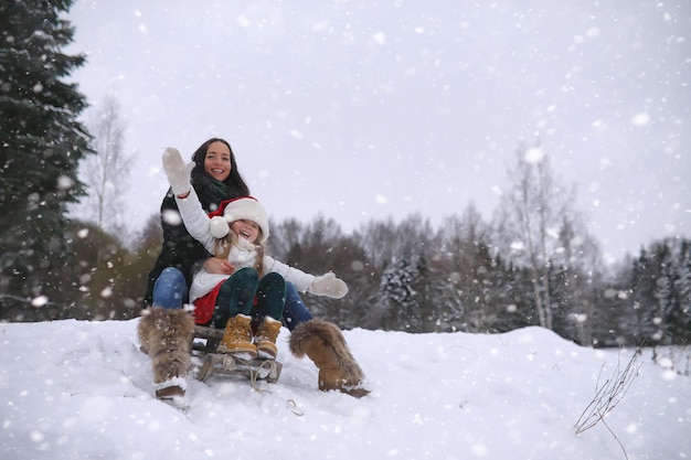 Conte de fées d'hiver une jeune mère et sa fille font du traîneau dans la forêt