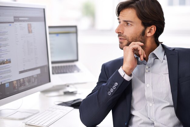 Contemplation sur le lieu de travail. Un jeune homme d'affaires faisant des recherches sur son ordinateur.