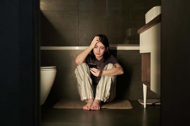 Contempler l'humeur en tenant le téléphone dans la salle de bain