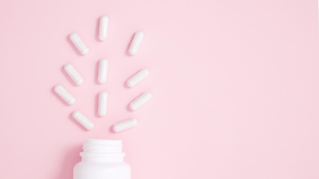 Conteneur de bouteille blanche avec des capsules de médicaments sur fond rose Concept de médecine de la santé