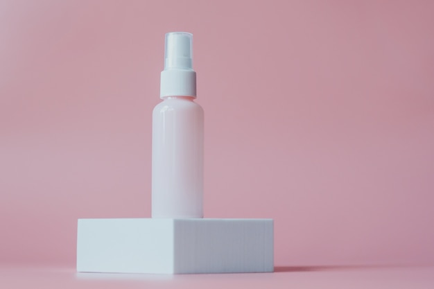 Conteneur de bouteille en plastique rose pour les cosmétiques, sur une plate-forme blanche