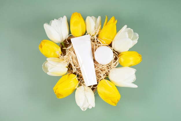 Conteneurs de bouteilles cosmétiques blanches sur boîte-cadeau autour de fleurs de tulipes