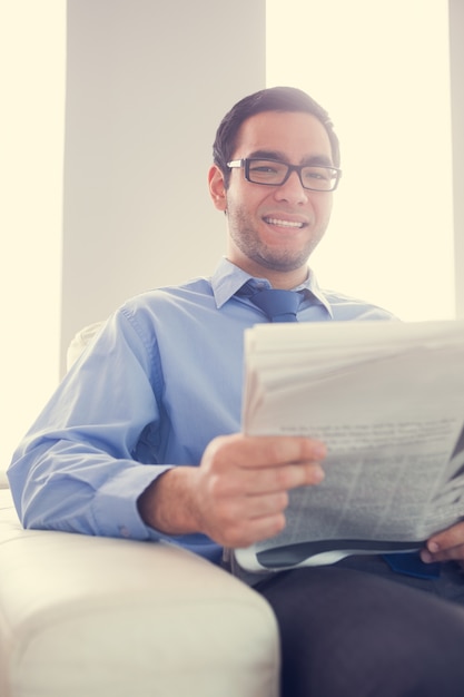 Content homme regardant et tenant un journal assis sur le canapé