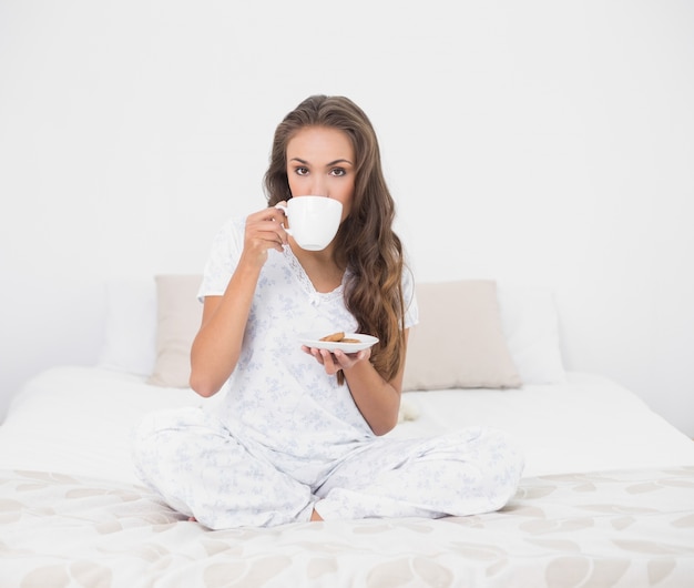 Content séduisante brune à boire dans une tasse