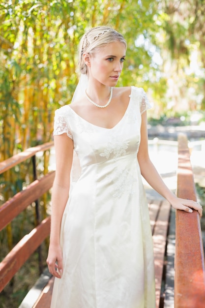 Contenu blonde mariée en collier de perles debout sur un pont