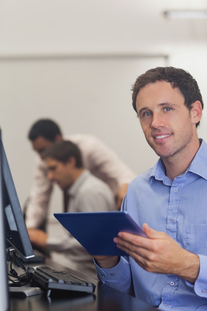 Photo contenu étudiant de sexe masculin tenant sa tablette assis dans un cours d'informatique