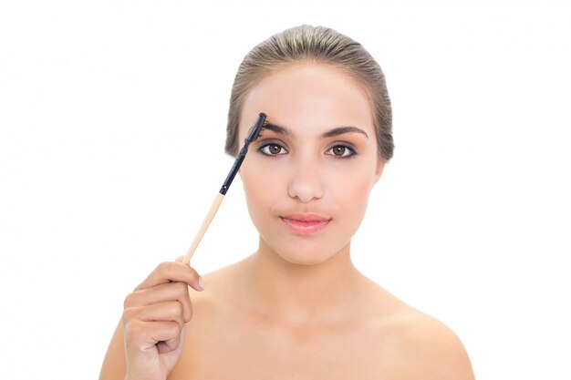 Contenu femme brune à l&#39;aide de la brosse à sourcils
