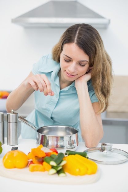 Contenu femme brune cuisine avec légumes debout dans la cuisine