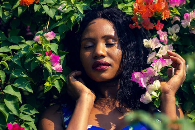 Photo contenu femme noire sentant les fleurs dans le parc.