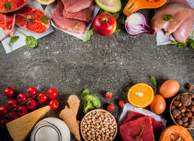 Contexte d'une alimentation saine. Ingrédients alimentaires biologiques, superaliments: viande de bœuf et de porc, filet de poulet, saumon, haricots, noix, lait, œufs, fruits, légumes. Table en pierre noire, vue de dessus du fond