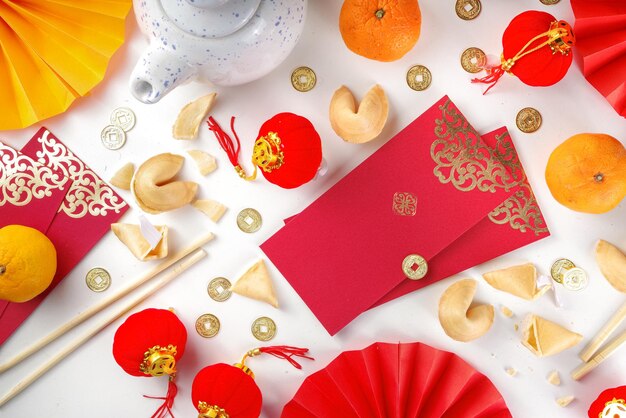 Contexte du nouvel an chinois. Flatlay rouge et jaune doré avec décor traditionnel du nouvel an chinois, enveloppes avec souhaits, pièces d'or, éventails, lanternes chinoises, oranges et thé