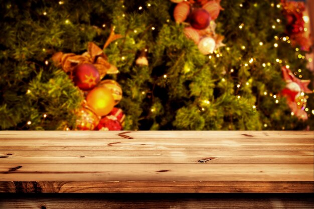 Contexte de Noël et Nouvel An avec une table de bois vide et sombre sur un arbre de Noël et un bokeh lumineux flou. Affichage vide pour le montage du produit. Fond d&#39;écran rustique vintage.