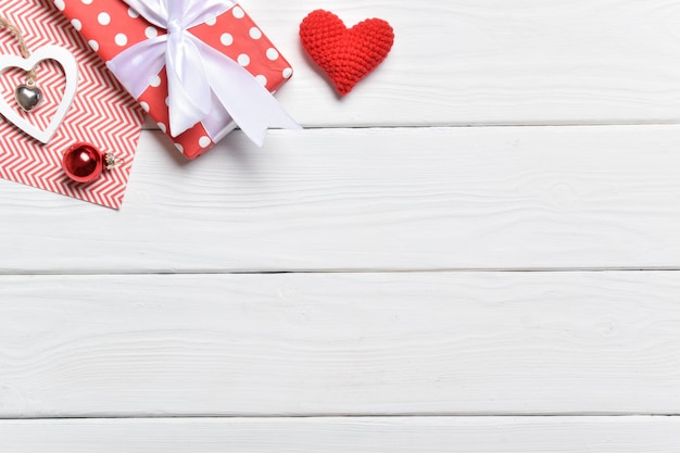 Contexte pour la Saint-Valentin. Cadeau et coeurs sur un fond en bois blanc