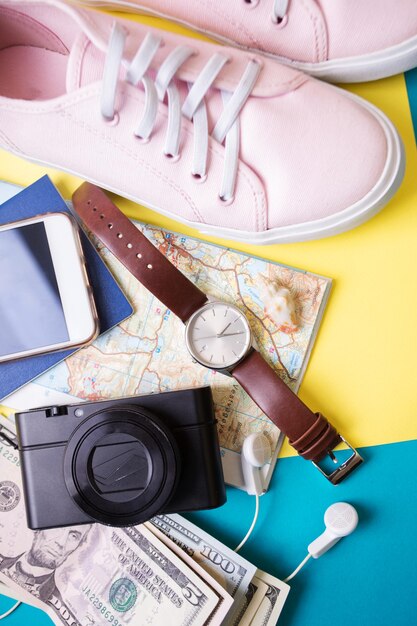 Contexte pour un voyage - montres, baskets, carte, dollars, lunettes, appareil photo, écouteurs, passeport