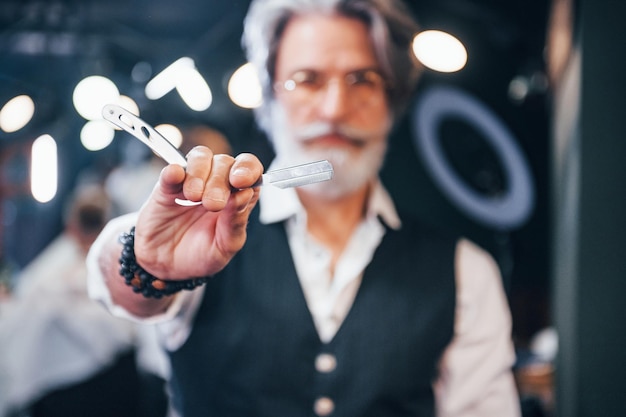 Contient l'équipement du salon de coiffure Un homme âgé moderne et élégant aux cheveux gris et à la barbe est à l'intérieur