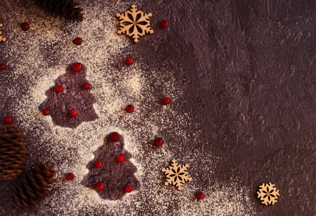 Le contour de l'arbre de Noël avec du sucre en poudre aux fruits rouges sur fond sombre