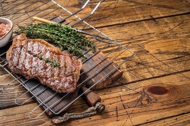 Contre-filet grillé ou steak de viande de bœuf de New York cuit sur un fond en bois BBQ Vue de dessus Espace de copie