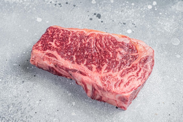 Contre-filet Wagyu cru ou steak de New York sur une table de boucher Fond gris Vue de dessus