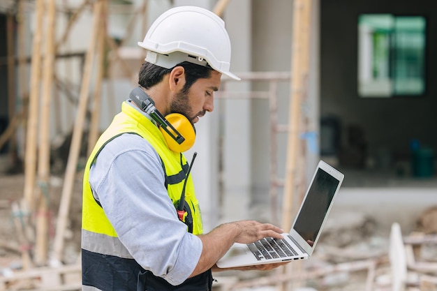 Contremaître ingénieur en construction travaillant en contact avec un ordinateur portable sur un chantier de construction