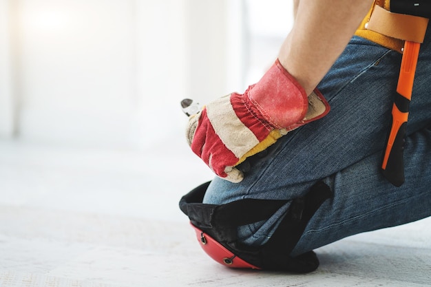 Contremaître d'installation effectuant la réparation des genouillères et des gants de protection au sol