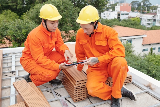 Contremaître avec tablette informatique expliquant les détails des travaux à l'entrepreneur en toiture