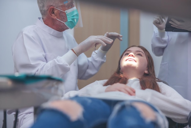 Contrôle des dents chez le dentiste, médecin effectuant un traitement dentaire sur une femme et une fille dans le cabinet du dentiste