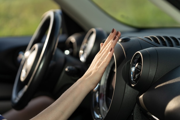 Contrôle de la main du panneau de climatisation dans la voiture femme conducteur tenant la main au système de climatisation