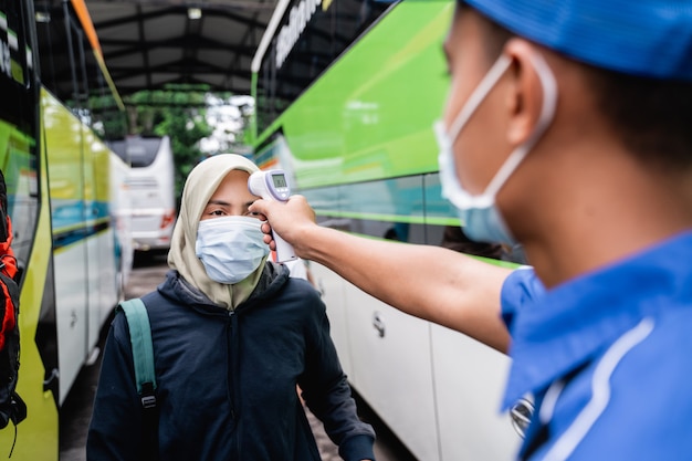 Contrôle de la température des passagers asiatiques à l'aide d'un thermogun avant de prendre le bus