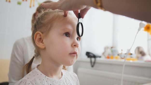 Contrôle de la vue en ophtalmologie de l'enfant - diagnostic d'optométriste petite fille, gros plan