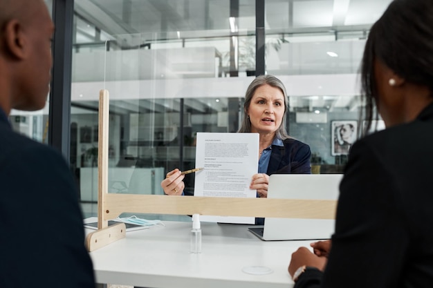 Photo les contrôles de sécurité font partie de notre protocole photo d'une femme d'affaires mûre ayant une réunion avec un pare-éternuements dans un bureau moderne