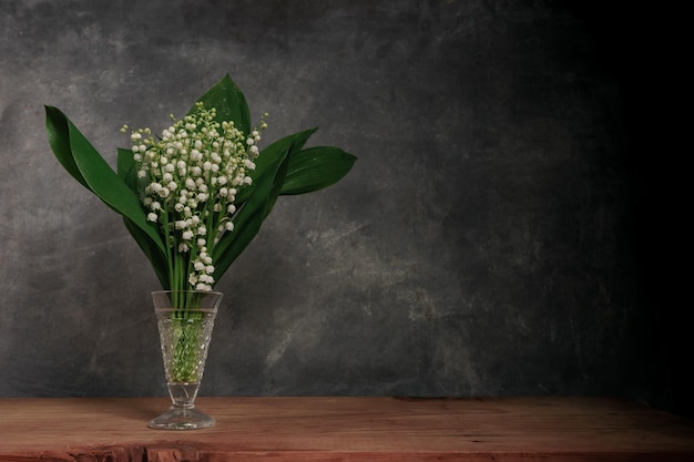 Convallaria majalis sur une table en bois rouge Un beau fond de mur gris