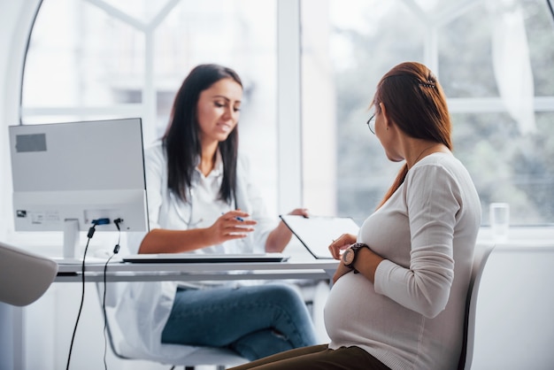 Conversation active. Une femme enceinte consulte un obstétricien à l'intérieur.