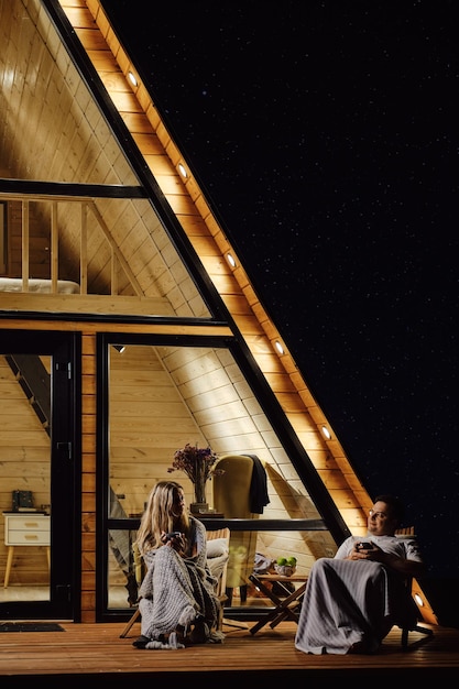 Conversation calme entre un homme et une femme sur la terrasse d'une cabane dans la soirée