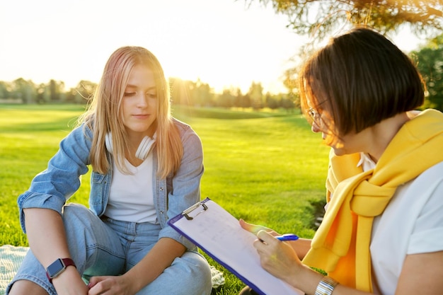 Conversation d'une jeune femme avec une assistante sociale psychologue en plein air lors d'une réunion dans un parc sur la pelouse