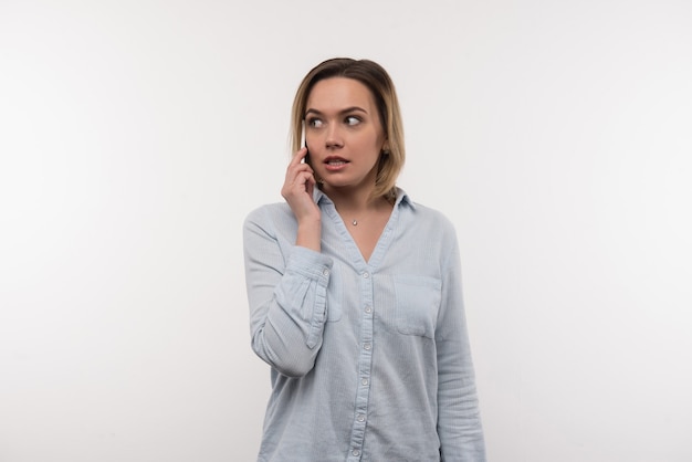 Conversation téléphonique. Agréable belle femme parlant au téléphone en se tenant debout sur fond blanc