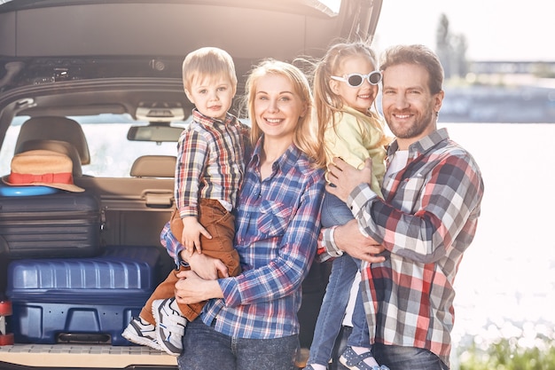 La convivialité est un ingrédient très important de la vie de famille La famille se tient près de la voiture à la recherche