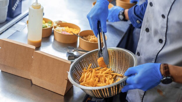 Cook ajoutant de la viande frite et des frites aux plats dans un food truck