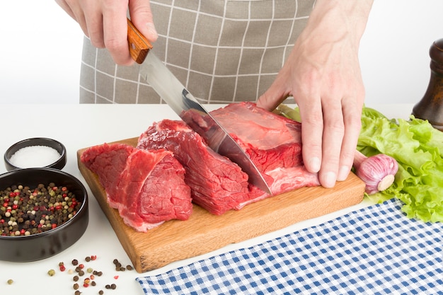 Cook coupe la viande crue sur une planche de bois