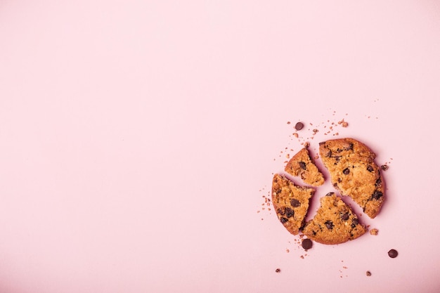 Cookie aux pépites de chocolat cassé et miettes sur fond rose