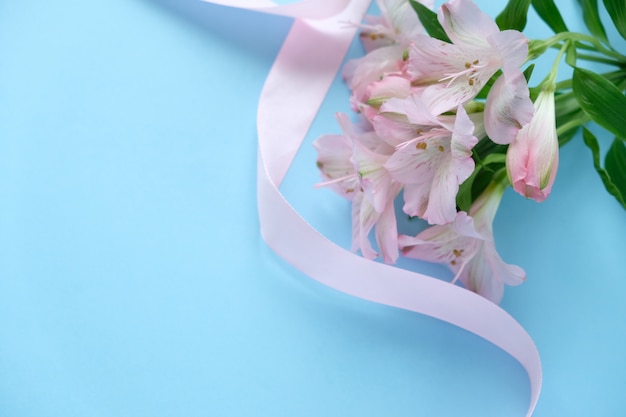 Cookies en forme d'ange avec un ruban rose avec lisianthuses sur fond bleu