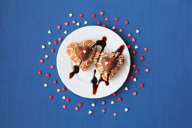 Cookies en forme de coeur sur une petite assiette blanche sur fond bleu