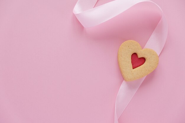 Cookies en forme de coeur avec un ruban rose sur un rose